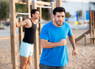 Fototapeta premium Portrait of adult man who is jogging when his friend is pulling-up