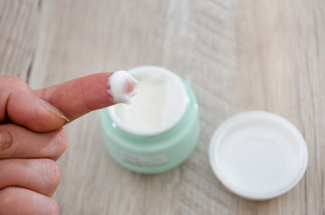finger takes face cream from jar