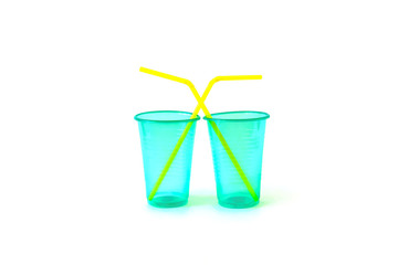 Green empty disposable plastic glasses with yellow drinking straws isolated on a white background.
