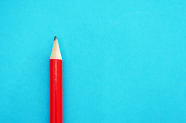red pencil on blue background. Close-up. Place for text.