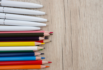 colored pencils and white pens on wooden background. Close-up. Place for text.