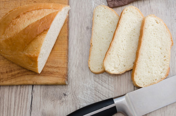 long loaf on a wooden board and knife. Delicious Ukrainian bread. Sliced white bread.