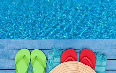 Flip-flops, beach towel and hat by the swimming pool