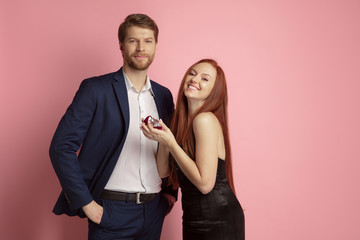 Will you merry me. Valentine's day celebration, happy caucasian couple isolated on coral studio background. Concept of human emotions, facial expression, love, relations, romantic holidays.