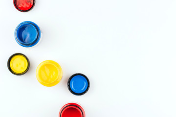Cans of acrylic paint in blue, red and yellow on a white background copy space. Artistic paints.