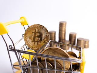 Pay crypto currency: the supermarket cart is filled with gold coins of bitcoin on a white background. Copy space