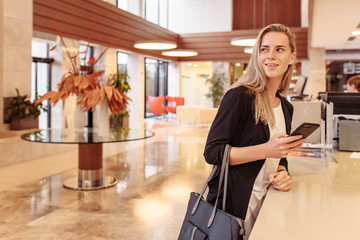 Positive smiling young woman, a blonde millennial, looks at mail in social networks and joyfully...