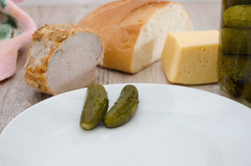 Ukrainian appetizer on a wooden table. Cucumbers, cheese, ham, bread.