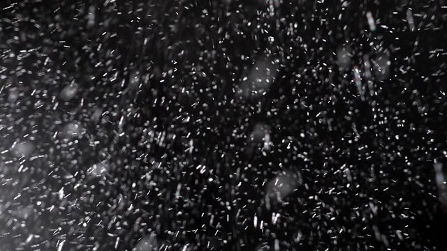 Real winter snow falling over isolated black background. Small snow flakes over dark night. Slow motion, 4K shot