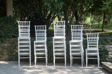 Exquisite wooden white chairs one on the other in garden