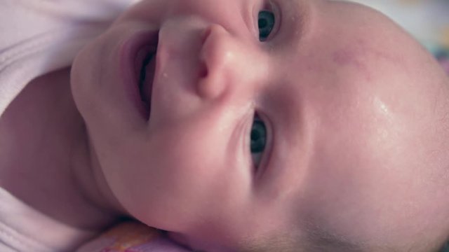 Portrait of a newborn baby girl. A newborn baby lies and looks away. Baby, first emotions, smile.
