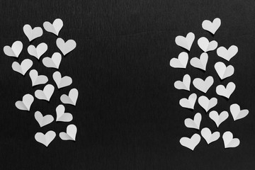 Simple greeting card with many white folded paper hearts on black backgound