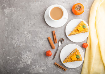 Homemade cake with persimmon and pumpkin and a cup of coffee on a gray concrete background. top view, copy space.