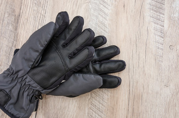 black snowboard gloves on a wooden background. View from above.