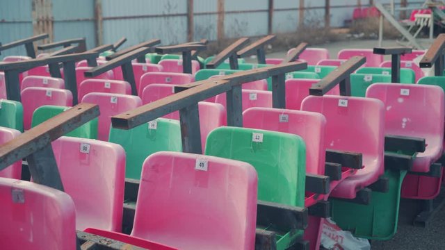 Landfill seats in different colors from the stadium. Abandoned game concept. Unnecessary sport. Stadium dumping chairs