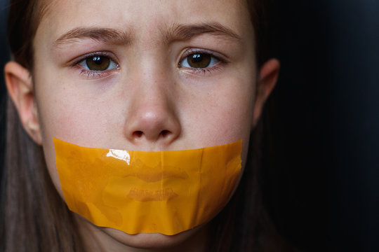 Unhappy girl with sticky tape over her mouth. Violation of human rights. Kidnapping.