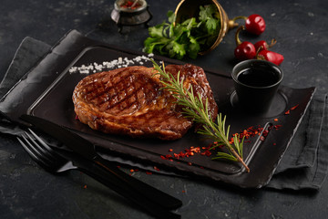 Grilled beef steak with rosemary and spices on dark background