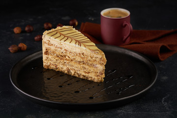 Piece of cake with nuts on black plate