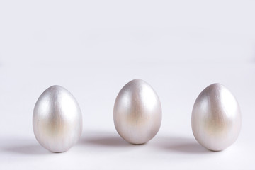 Easter holiday composition. Three eggs of silver color on a white background. Easter flat ley. Easter concept. Copyspace.