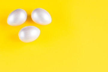 Easter holiday composition. Three eggs of silver color on a yellow background. Easter flat ley. Easter concept. Copyspace.