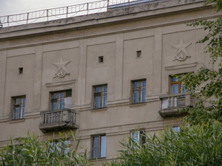 Upper balconies of the building with stone stucco sickle, hammer and star