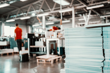 Picture of printing shop interior. Selective focus on pile of sheets. - obrazy, fototapety, plakaty