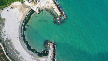 Aerial top down view of Bolata Cove on Black sea, Bulgaria. White sand beach on the sea shore near cape Kaliakra. Stones, foaming waves, sunbathing people and colorful boats from above.