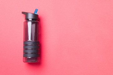 black plastic sport bottle lying on left side of red background with copyspace