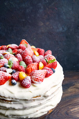 Homemade white cream cake with fresh berries on rustic wooden table, dark background with copy space. Beautiful, tasty dessert made of natural products. Selective focus. Holiday, birthday food concept
