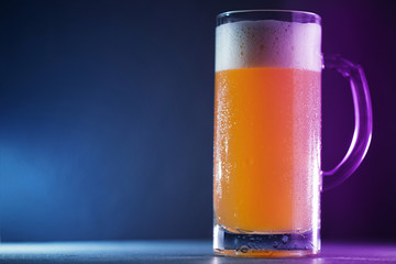 A mug of cold wheat beer on a dark blue background