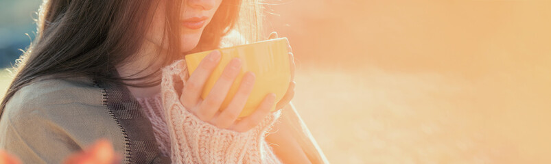Portrait of pretty young woman in stylish knitted sweater standing on the golden autumn forest on sunny day, Time to relax and have some coffee