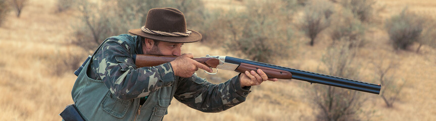 Hunting period, autumn season open. A hunter with a gun in his hands in hunting clothes in the...