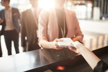 Close-up of businesswoman standing near the reception and taking brochure for business conference