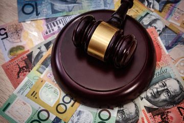 Money and justice. Wooden judge's gavel with colorful australian dollar banknotes close up
