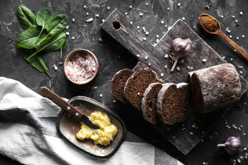 Sliced bread with butter and pieces scattered on a dark background