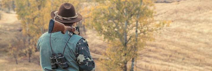 Hunting period, autumn season open. A hunter with a gun in his hands in hunting clothes in the...