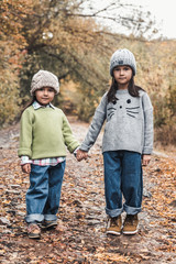 Little cute smiling girls walking together in autumn day. Friendship. Happy family concept