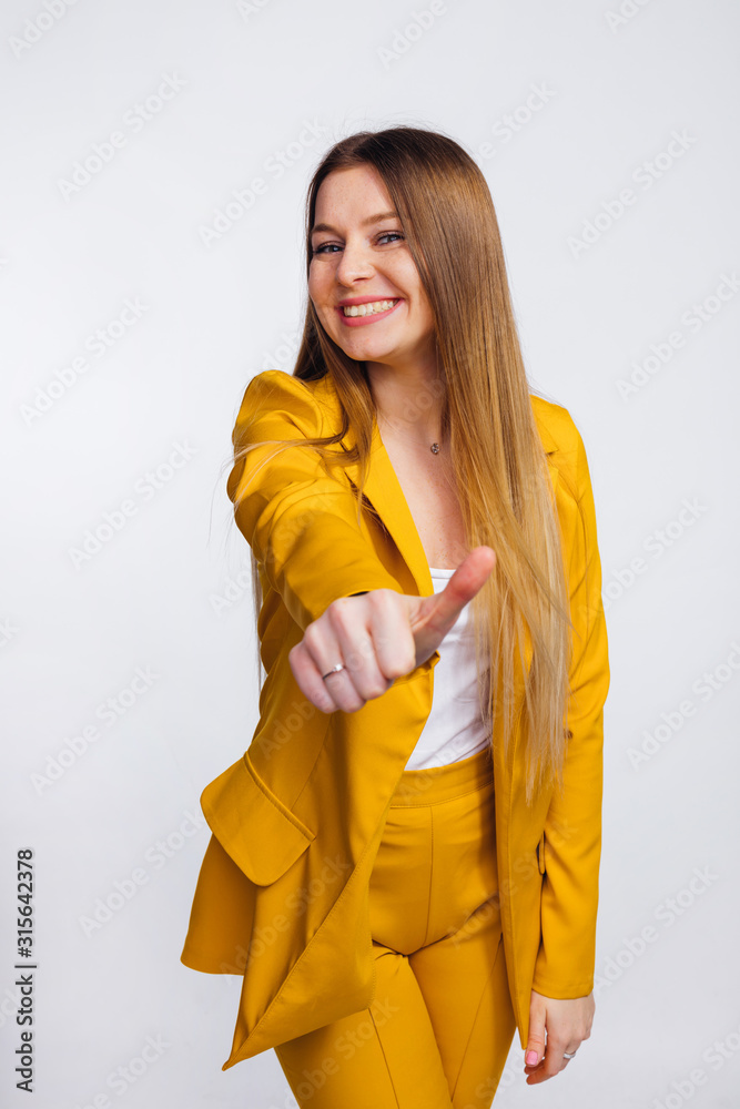 Wall mural girl with long hair shows a gesture and smiles. she is dressed i