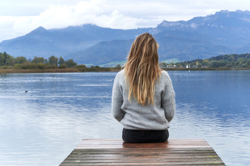 Fototapeta premium Woman in a jetty facing the lake