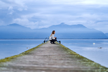 Fototapeta na wymiar Woman in a jetty facing the lake