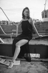 Woman in black dress on beach with broken ships