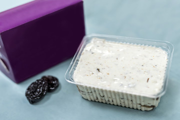 Delicious dessert in plastic package with prunes on table and violet wrapping close up. Food concept