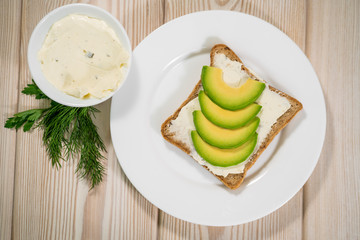 Avocado toast with egg whites and pea shoots on wooden board, overhead view