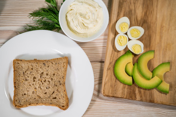 Avocado toast with egg whites and pea shoots on wooden board, overhead view