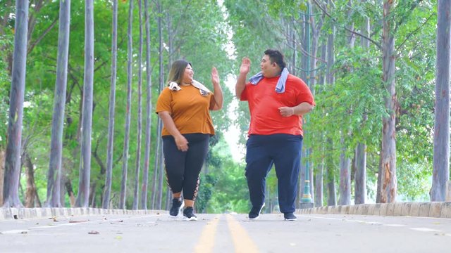Happy overweight couple running at the park while clapping hands. Shot in 4k resolution