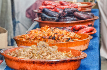 Different meats cooked at outdoor by a street restaurant. Focus over the pork rinds. Barbecue with...