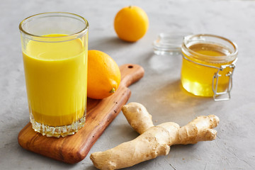 Health concept. Golden milk, ginger, lemon, honey on a grey concrete background. Health and energy boosting, flu remedy, natural cold fighting drink. Clean eating, detox, weight loss concept.