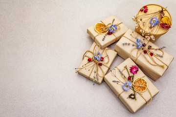Zero waste gift concept. Valentine Day or Birthday eco friendly packaging. Festive boxes in craft paper with different organic decorations. Stone concrete background
