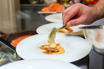 chef puts sauce on a shrimp cocktail in a restaurant, the finished dish