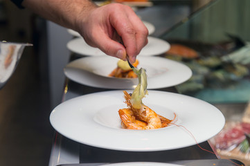 chef puts sauce on a shrimp cocktail in a restaurant, the finished dish